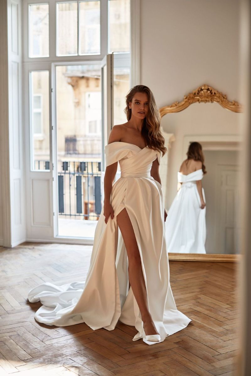 Robe de mariée d'occasion avec col bardot, jupe évasée et fente sur le côté